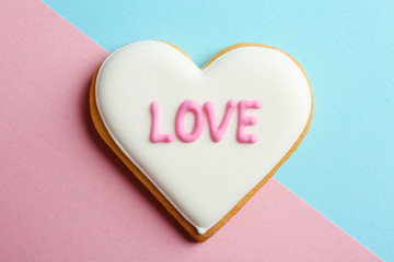 Decorated heart shaped cookie with word LOVE on color background, top view. Valentine's day treat