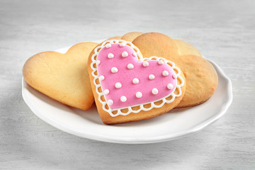 Plate with decorated heart shaped cookies on wooden table