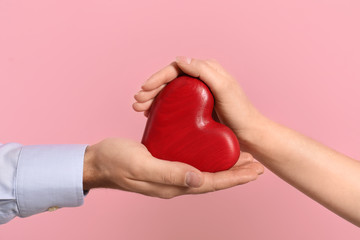 Man and woman with decorative heart on color background, closeup