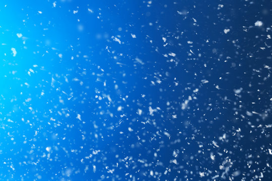 Snow flakes falling on blue background. Winter weather