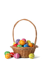 Decorated Easter eggs in wicker basket on white background