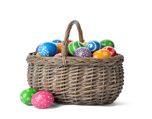 Decorated Easter eggs in wicker basket on white background