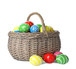 Decorated Easter eggs in wicker basket on white background
