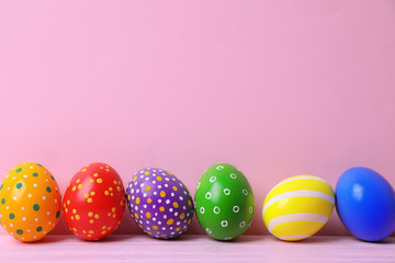 Decorated Easter eggs on table near color wall. Space for text