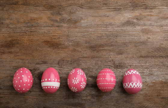 Decorated Easter eggs and space for text on wooden background, top view