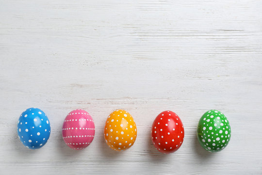 Decorated Easter eggs and space for text on wooden background, top view