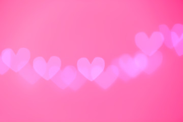 Fototapeta na wymiar Blurred view of beautiful heart shaped lights on color background