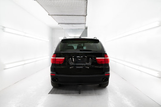 Black car in white paint booth