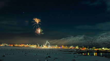 New years fireworks over town of Hauganes, Iceland