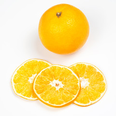 Dried orange slices next to fresh orange on a white background