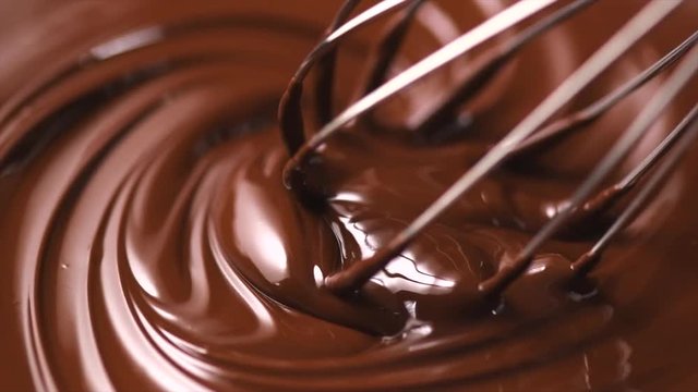 Chocolate. Mixing melted dark chocolate with a whisk. Closeup of liquid hot chocolate swirl. Confectionery. Slow motion 4K UHD video 3840X2160