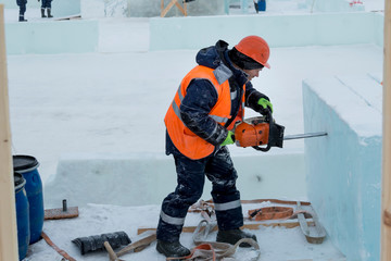Fototapeta premium Portrait of a fitter in an orange vest with a chainsaw in his hands