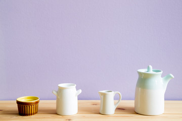 Ceramic tableware on wooden table with light purple background