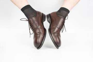 Male legs in socks and brown classic shoes on a white background