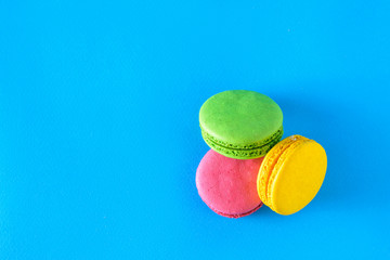 Yellow, green and red macaroons on blue background. The view from the top.