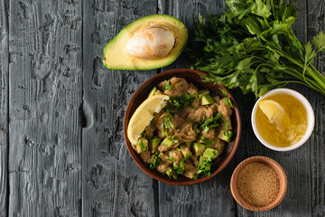 Clay bowl with amaranth seed salad with avocado, lemon, tomatoes and parsley and bowl with amaranth on a rustic table. The view from the top.