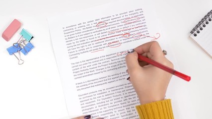 Teacher correcting an exam or homework with a red marker pointing out all the errors in the text.