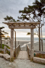 Japanese-style archway decorates stairway heading down to a Pacific coast beach in Washington state. Pacific ocean can be seen in background.