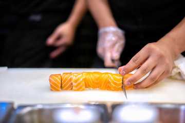 Japanese chef making sushi at restaurant. Traditional Japanese food, salmon sushi roll.