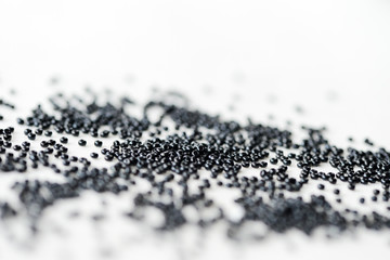 Seed beads of black color scattered on textile background close up