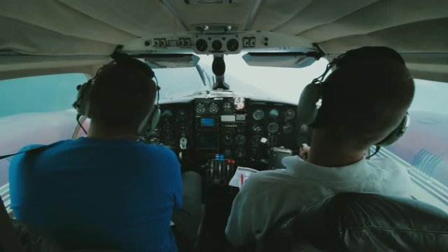 Inside the Cockpit of a Small Turboprop Piper Aircraft. Two Male Pilots Can be Seen Operating the Controls and Flying the Plane. Flight Conducted Over the Gothenburg Archipelago