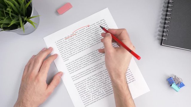 Teacher correcting an exam or homework with a red marker pointing out all the errors in the text.