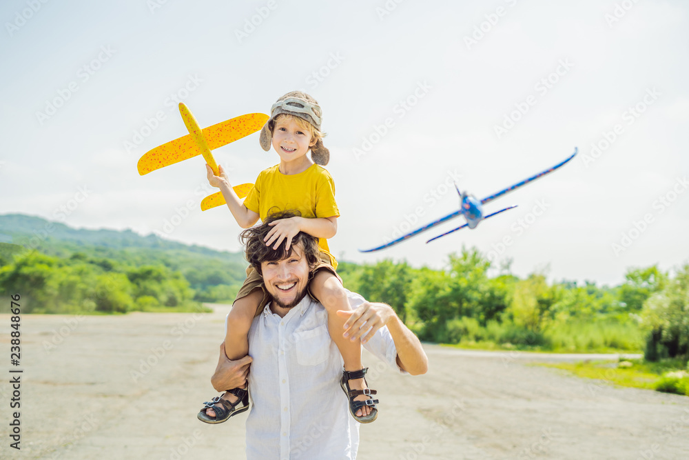 Wall mural happy father and son playing with toy airplane against old runway background. traveling with kids co