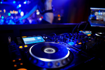 DJ console cd mp4 deejay mixing desk Ibiza house music party in nightclub with colored disco lights.