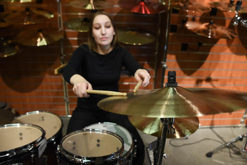 Fototapeta na wymiar Professional drum set closeup. Beautiful young woman drummer with drumsticks playing drums and cymbals, on the live music rock concert or in recording studio 