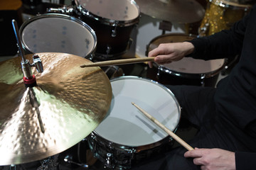 Professional drum set closeup. Man drummer with drumsticks playing drums and cymbals, on the live music rock concert or in recording studio   