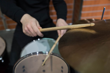 Professional drum set closeup. Man drummer with drumsticks playing drums and cymbals, on the live music rock concert or in recording studio   