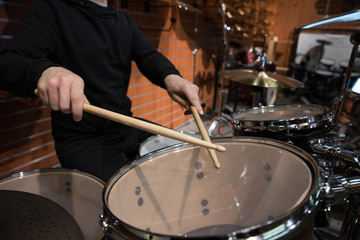 Professional drum set closeup. Man drummer with drumsticks playing drums and cymbals, on the live music rock concert or in recording studio   