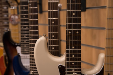 Fototapeta premium Closeup of row of different colorful guitars on the display for sale hanging in a music shop 