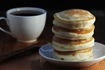A stack of freshly backed pancakes and a cup of coffee