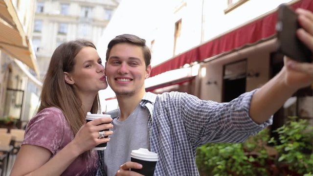 Couple Making Photo On Phone And Drinking Coffee At Street