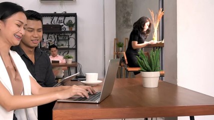 Two workers are working together at cafe.