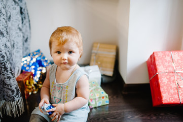 Portrait happy little girl playing with toys, sits on the background gifts. Festive birthday concept. baby on photo. infant. Women's Day, eighth of March. merry Christmas, happy holidays. new year.