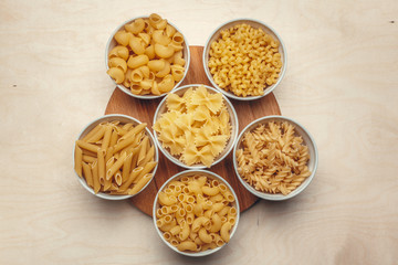 Different pasta types in bowls on the table.