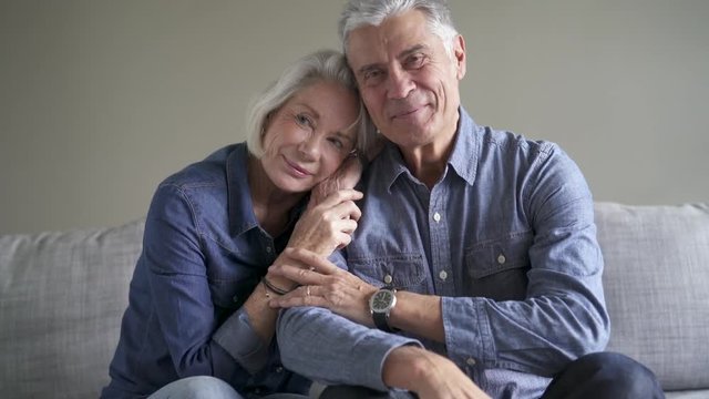 Loving senior couple smiling together on couch