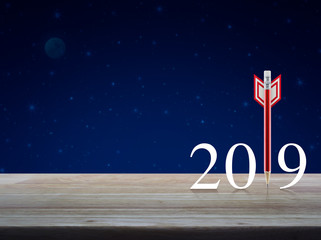 Red pencil in the shape of a dart with 2019 white text on wooden table over fantasy night sky and moon, Business strategy happy new year 2019 concept