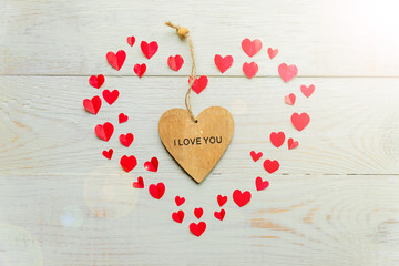 Big red heart made of cut out paper small hearts and wooden heart with I love you inscription on wooden backround. Handmade decoration for Valentine's day.