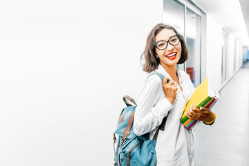 Portrait of a happy girl student or young teacher with backpack and books in university campus