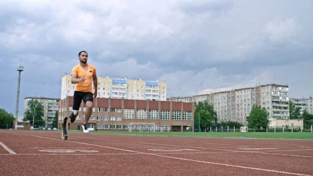 Strong amputee blade runner running on stadium track and crossing finish line