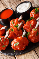 Delicious Deep frying Lollipops chicken wings with sauces close-up on a slate board. vertical