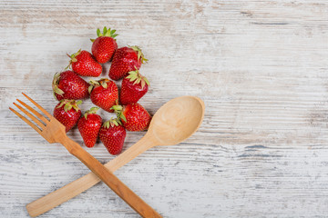 Summer vitamin food. Lots of fresh ripe fragrant strawberries and a wooden spoon and fork, lie on a...
