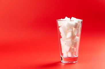 glass with sugar cubes on a red background