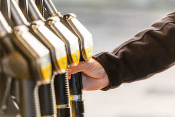 Hand with fuel nozzle at a gas station