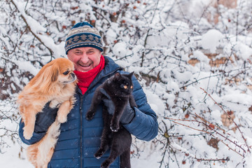 Senior man on a walk with black cat and red dog. Positive lifestyle and life after 50 -60 year. Good mood and holiday joyful with pets