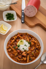 Typische DDR Soljanka Suppe in Schale mit Schmand und Zitrone