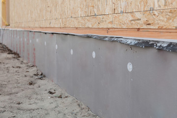 Close up photo of foundation new house covered drywall under wooden oriented strand board